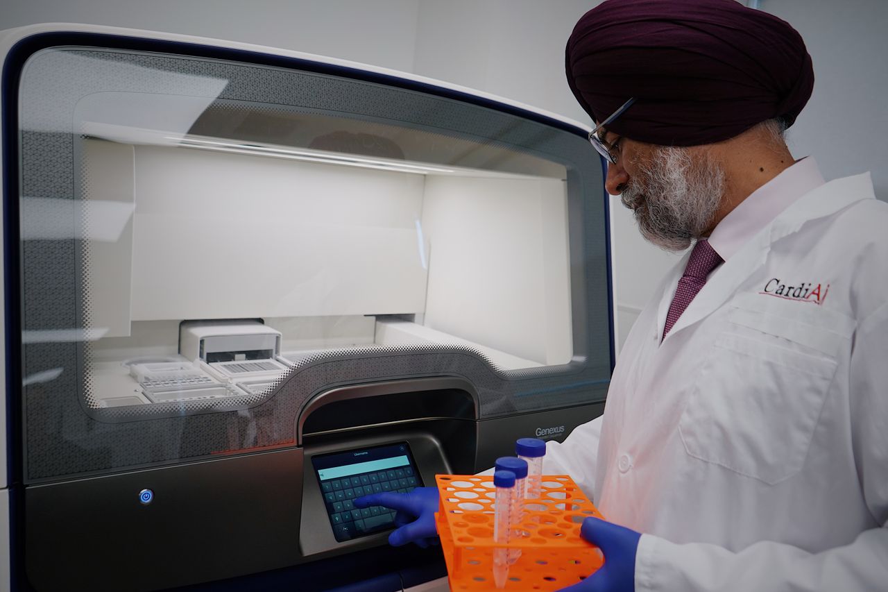 Services Researcher in lab analyzing samples with high-tech equipment. Wearing protective lab gear.