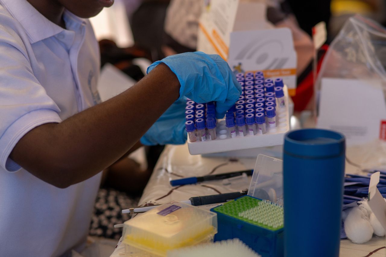 Home A healthcare professional organizing test tubes in a lab, focusing on precision and care.