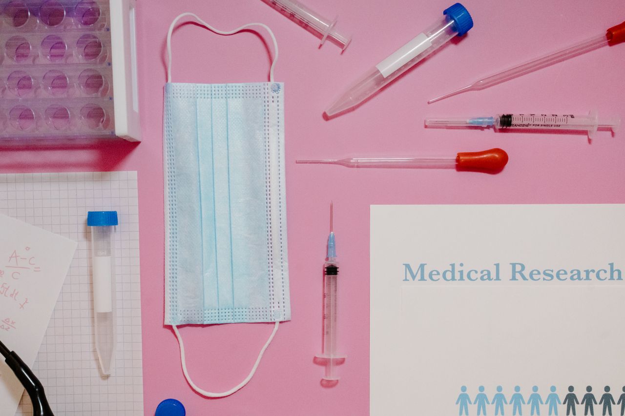 Home Flat lay of medical research tools and supplies on a pink background.