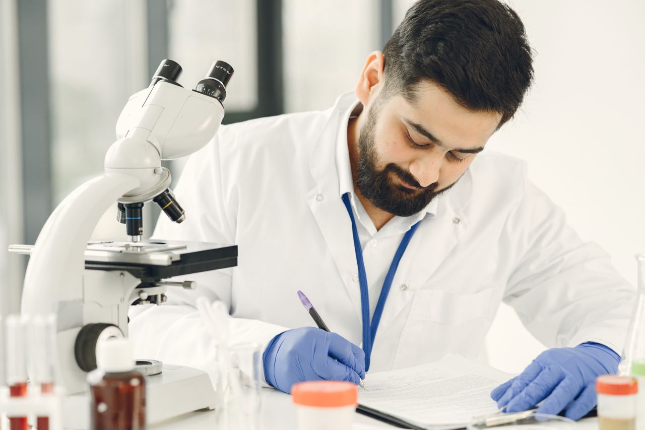 Home Male scientist in a laboratory, examining samples and taking notes.
