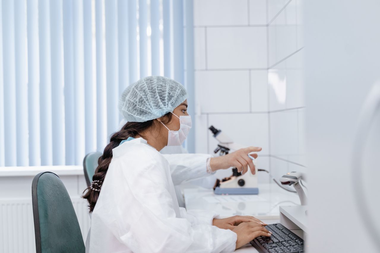Home Female scientist in laboratory coat working at computer in a clean, modern lab.